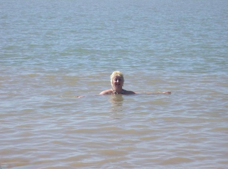 Older blonde amateur Mary Bitch takes a pee before going topless in the ocean