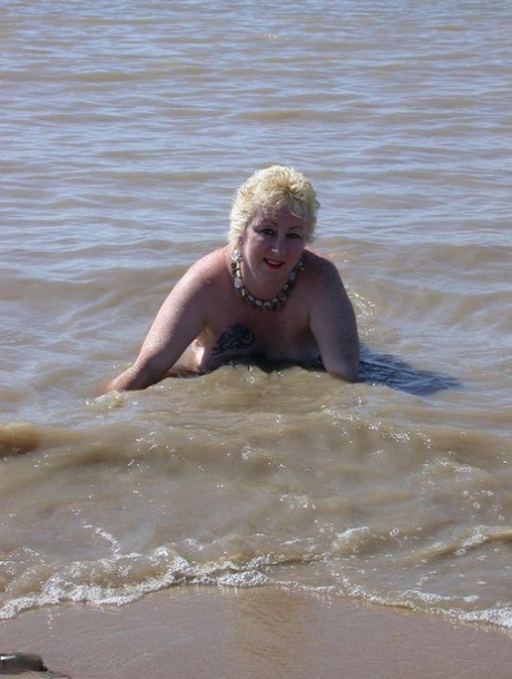 Older blonde amateur Mary Bitch takes a pee before going topless in the ocean