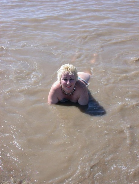 Older blonde amateur Mary Bitch takes a pee before going topless in the ocean