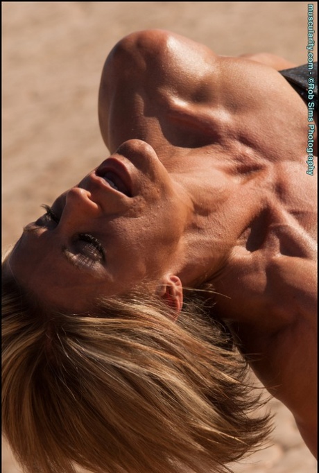 Older blonde bodybuilder Tracy Weller flexes on parched soil during SFW action
