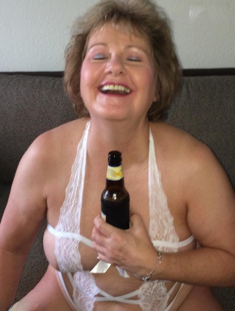Older amateur Busty Bliss drinks a beer while wearing revealing lingerie