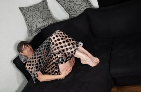 Mature woman with short hair gets totally naked on a sofa in glasses