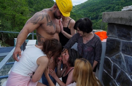 Insatiable mature women share a muscular dude's dick in an orgy on the rooftop