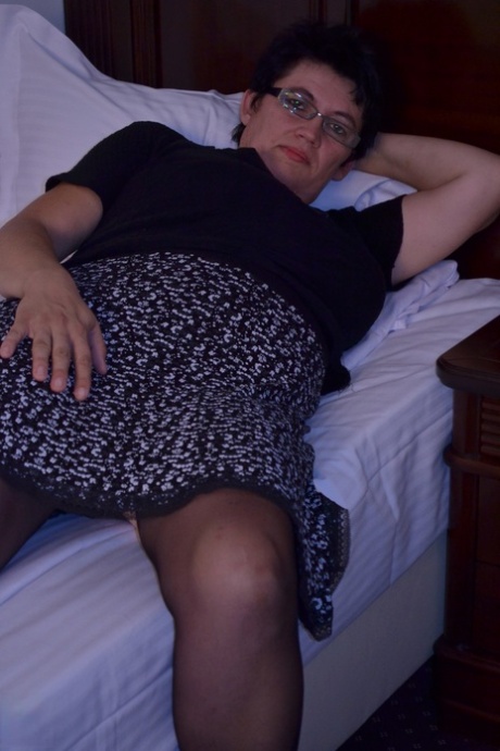 Short haired aunty in glasses Charlotte rubs and toys her clam on a bed