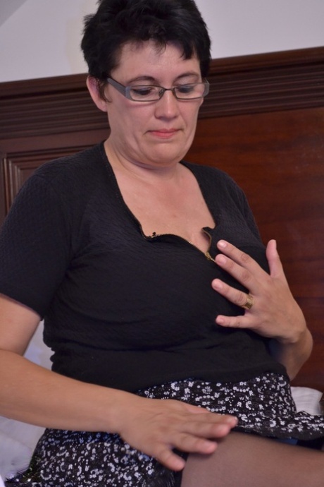 Short haired aunty in glasses Charlotte rubs and toys her clam on a bed